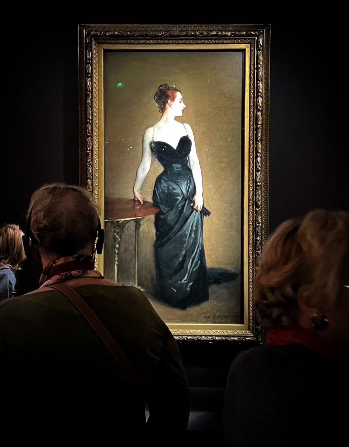 Sargent’s Madame X in its gilt frame at the Metropolitan Museum of Art, seen past two visitors
