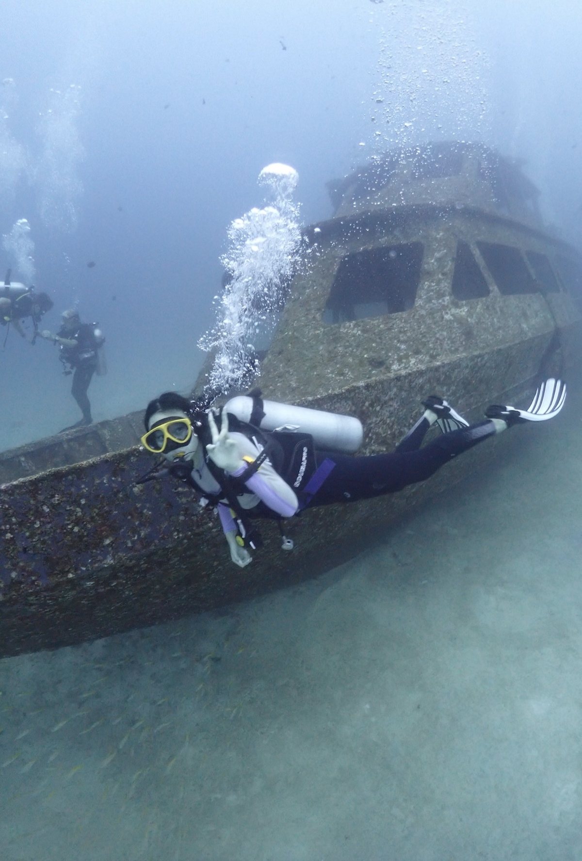 Diver giving an OK sign beside a sunken wreck