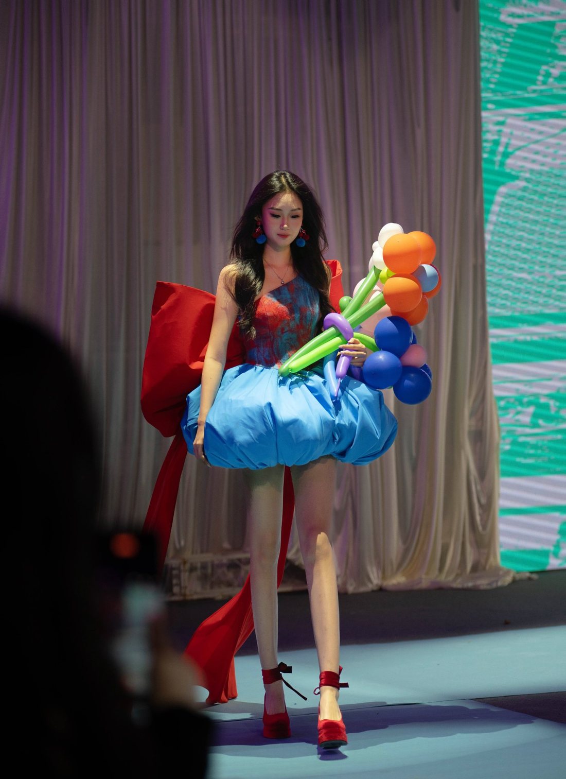 On the school runway in a balloon-skirt look with oversized props