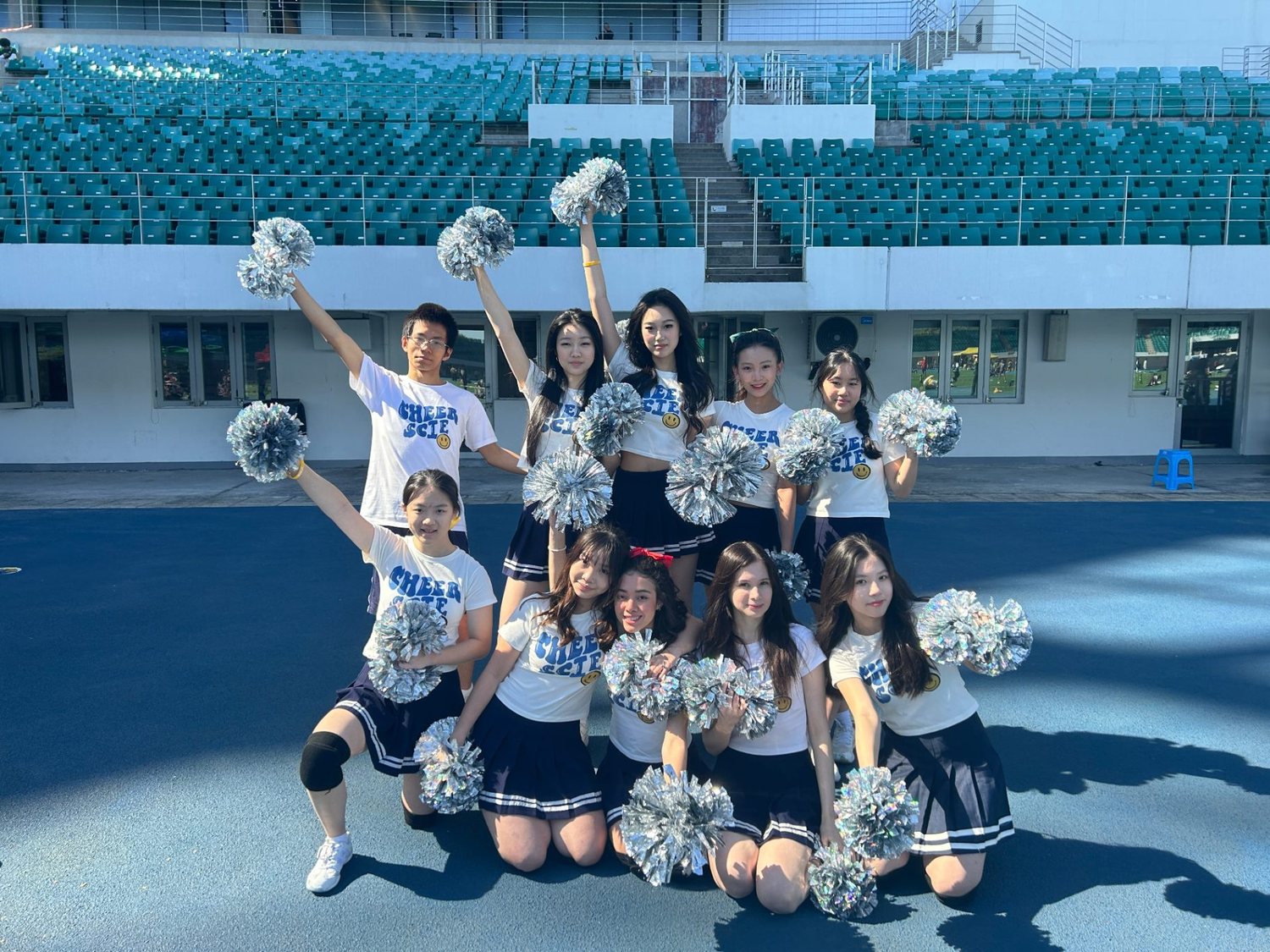 The school cheerleading team posing with pom-poms in the stadium